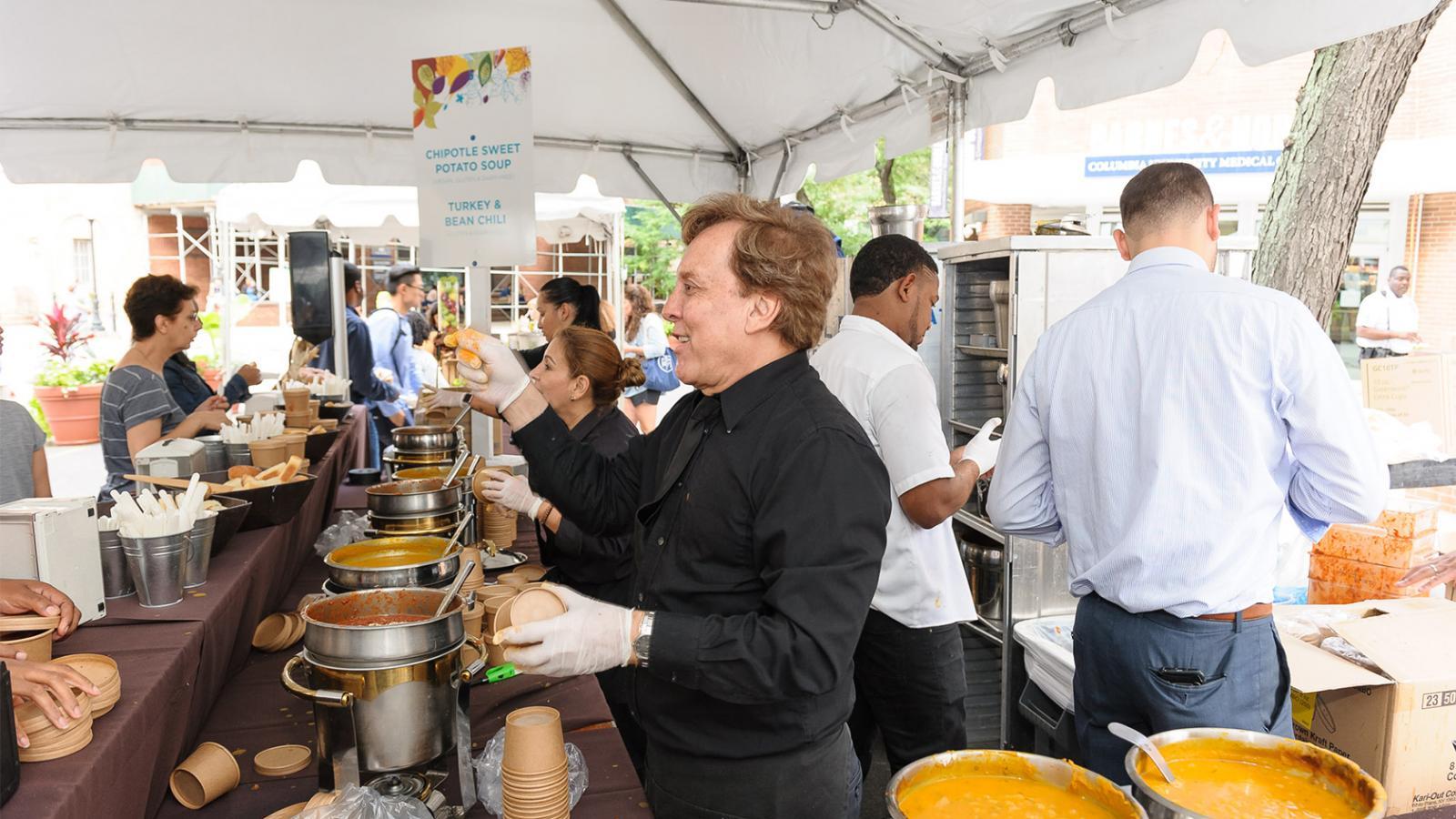 Faculty Club staff serving soups under an open-air tent