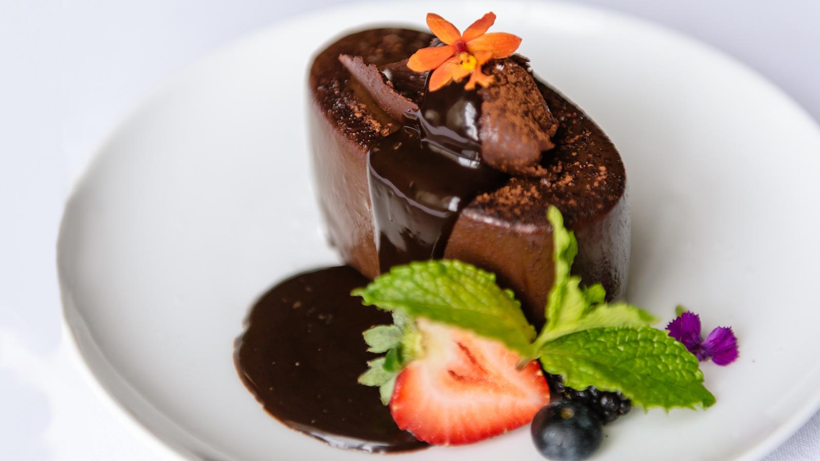 Chocolate truffle cake with a slice of strawberry and mint