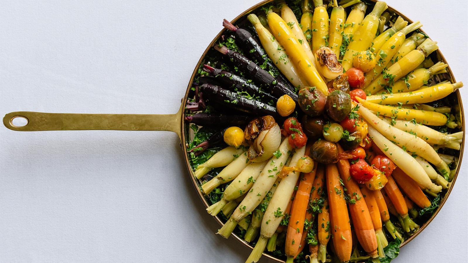 A pan filled with carrots and different types of squash along with cherry tomatoes.