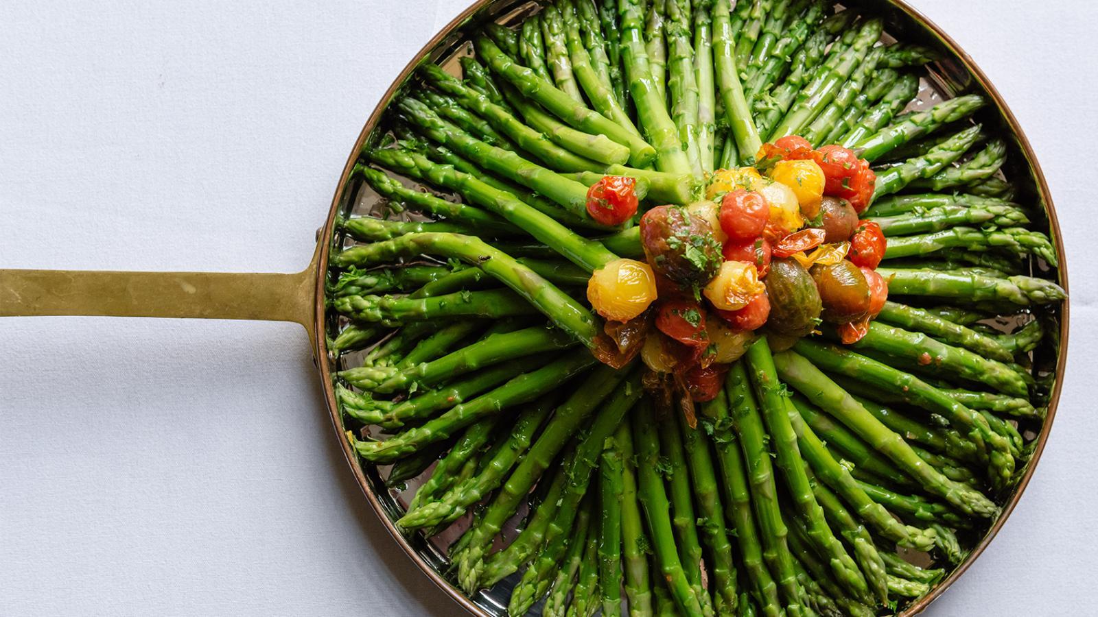 A pan of asparagus with cherry tomatoes.