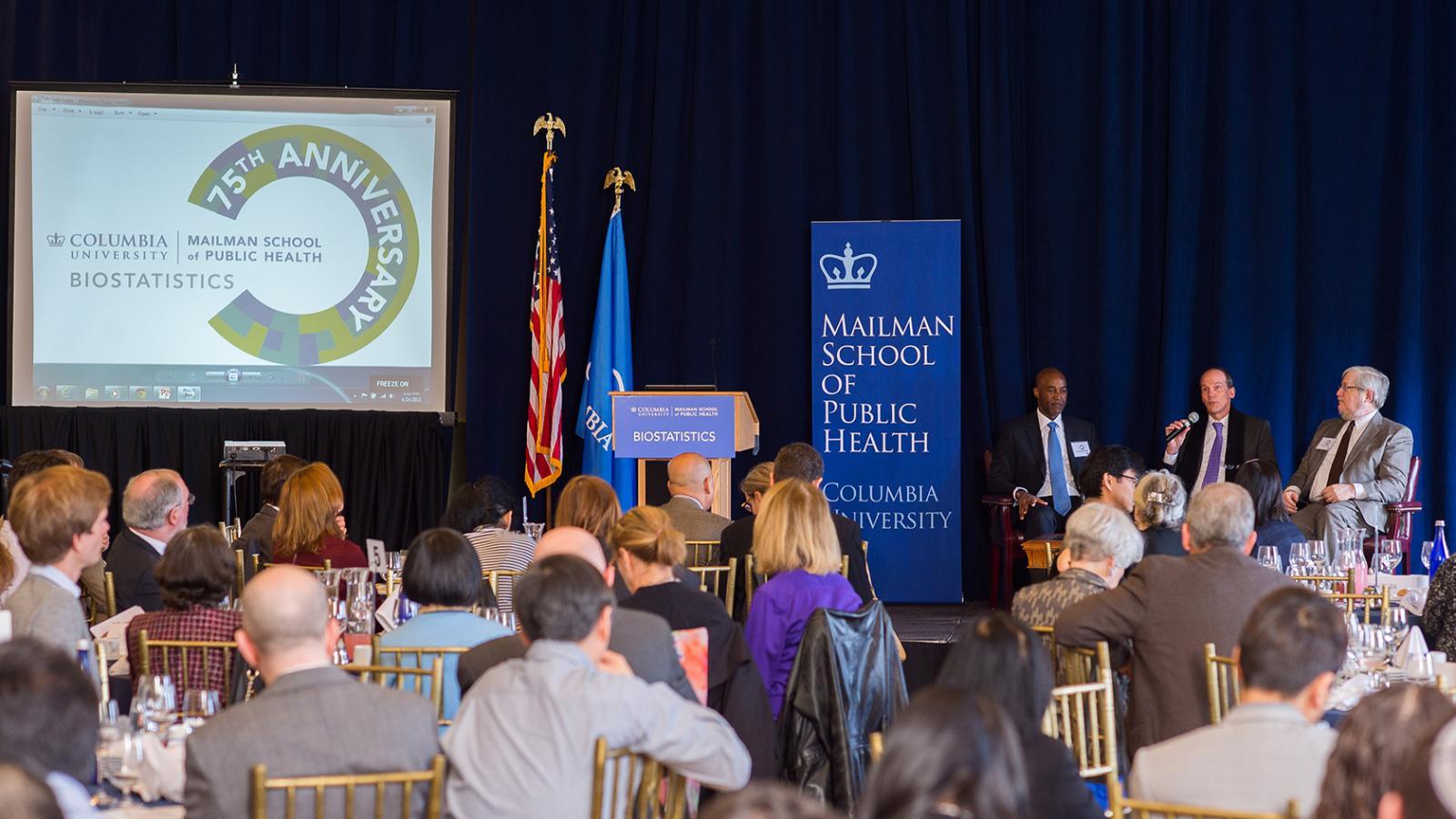 Bard Hall lounge with a panel of speakers, a Powerpoint presentation, and guests seated at tables