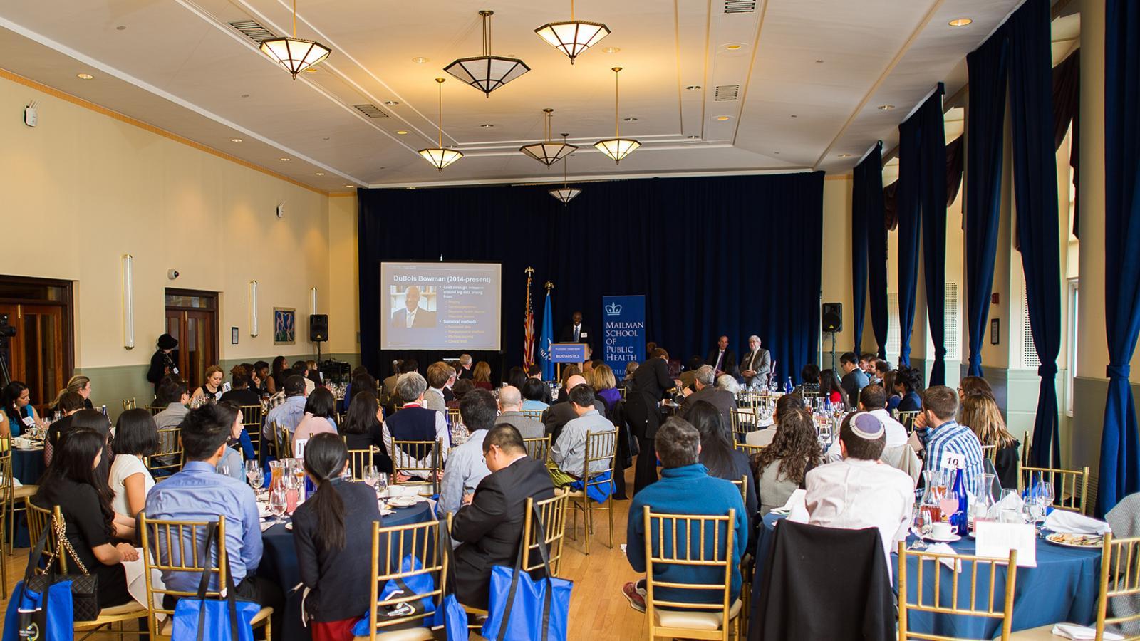 Bard Hall lounge with a Powerpoint presentation and guests seated at tables