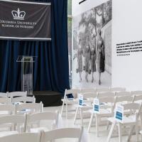 School of Nursing lobby: New building dedication, June 2017. White event spaces with rows of chairs. At the front, podium with pipe and drape